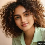 곱슬머리 전용 헤어크림 추천 - A close-up portrait of a young Indian woman with natural curly hair wearing a light cotton blouse, a...